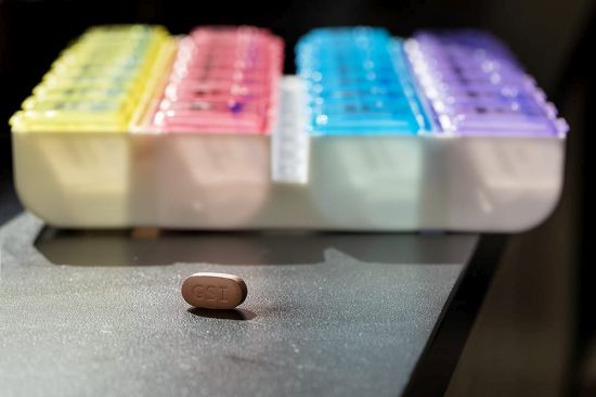 A Biktarvy pill that contains three medicines to treat HIV sits in front of a colorful pillbox. Photo by Sarah Pack