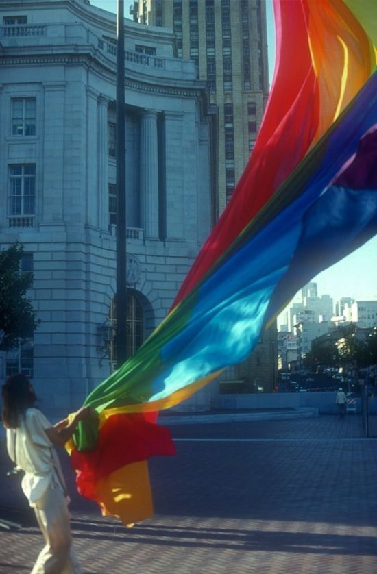 Gilbert Baker holds the first Rainbow Flag as it begins to fly at the United Nations Plaza in San Francisco