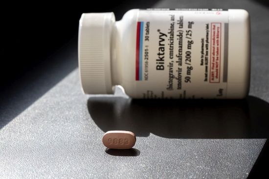 Pill bottle labeled Biktarvy lying on its side with a single brown pill in front of it