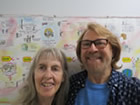 Photo: Peg Frank, living with HIV since 1997, and Bradford McIntyre, living with HIV since 1984, standing in front of the HIV In My Day Interactive Timeline by Peg Frank, at the AIDS Vancouver 40TH Anniversary, August 9, 2023.