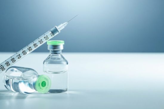 Vaccine in vial and syringe close-up on a white table gray background