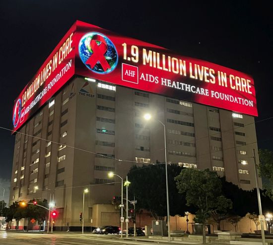 In honor of World AIDS Day, AIDS Healthcare Foundation (AHF), the worlds largest HIV/AIDS health care organization, has taken over the largest digital sign on the West Coast. AHFs message  “1.9 Million Lives in Care”  will show every couple minutes all day Friday on three sides of the building located on Broadway off the I-10 in downtown Los Angeles. Freeway commuters have a clear view of the buildings display.