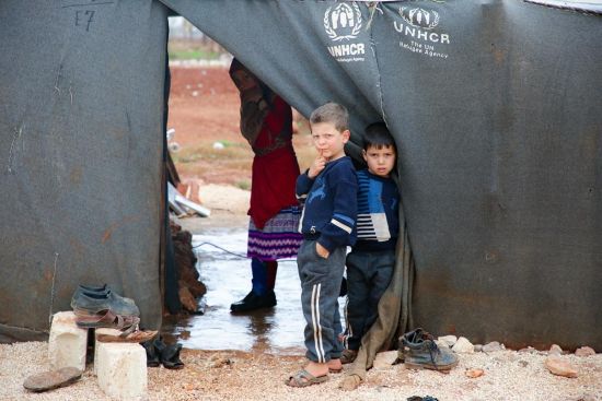 Two boys peak out from a UNHCR tent.
