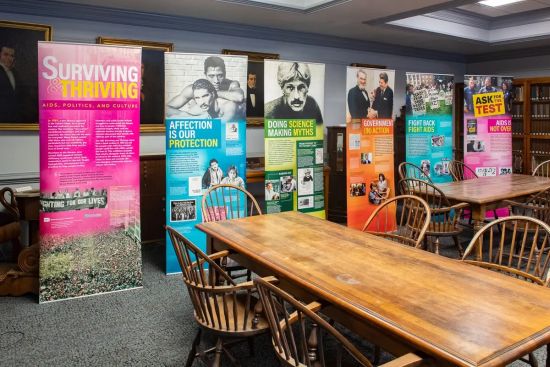 A photo of a room with tables with six banner signs with information on them